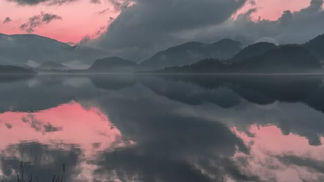 Dramatischer-Rosa-Sonnenuntergangshimmel-Mit-Dunklen-Gewitterwolken,-Die-Sich-Im-Stillen-Wasser-Spiegeln-Und-Einen-Jenseitigen-Anblick-Schaffen