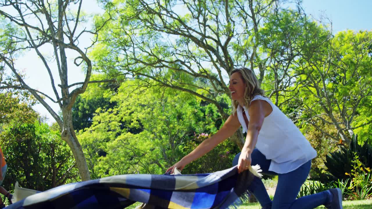 피크닉 담요 를 퍼뜨리는 어머니 와 공원 4k 에서 축구 를 하는 아들