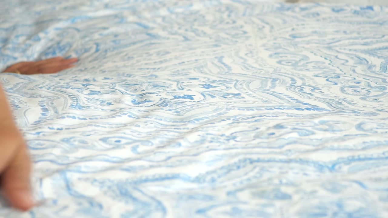 침대 위 에 패턴 을 가진 침대 의 옷 을 매끄럽게 하는 사람