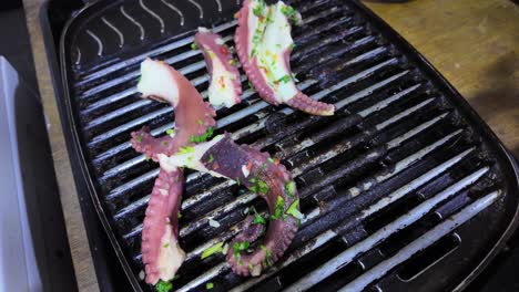 man hands flip tentacles while cooking octopus on a barbecue grill. seafood texture