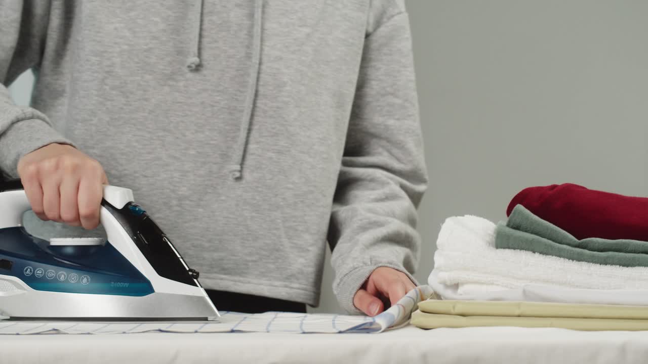 Hands Ironing a Striped Cloth on an Ironing Board
