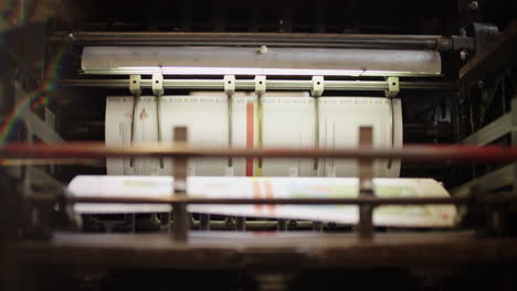 inside of a printing machine, papers moving down from the rollers on to the forks of the machine