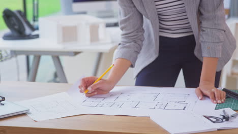 close up of female architect in office standing at desk working on plans for new building