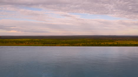 Hombre-Saltando-A-La-Piscina-Infinita-Del-Resort-En-Serengeti,-Tanzania