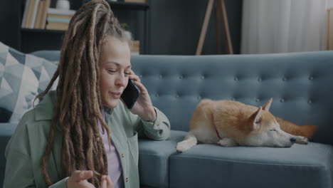 woman talking on phone while dog sleeps on couch