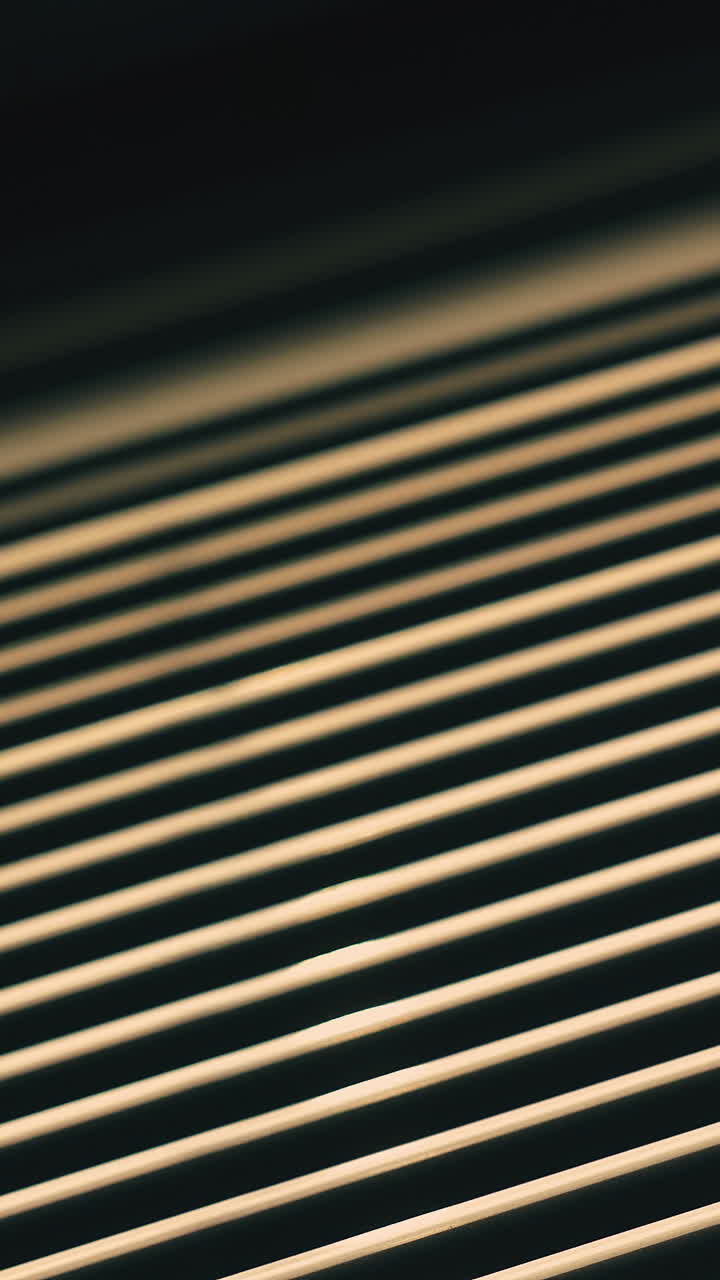 CU, Low angle shot: modern closed horizontal blinds on window against bright backlight in dark room close view