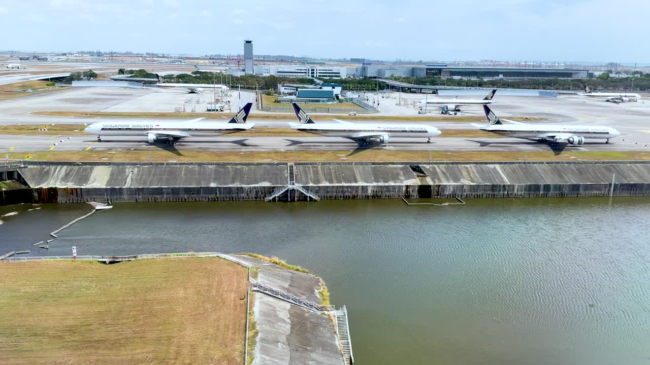 Toma aérea de dron de aviones comerciales estacionados en un aeropuerto tropical cerca del agua