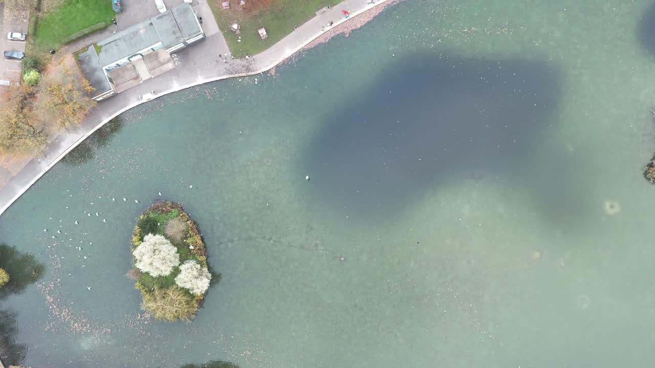 An aerial view captures a serene lake in Bochum, Germany, featuring a small, tree-covered island, offering a peaceful natural escape.
