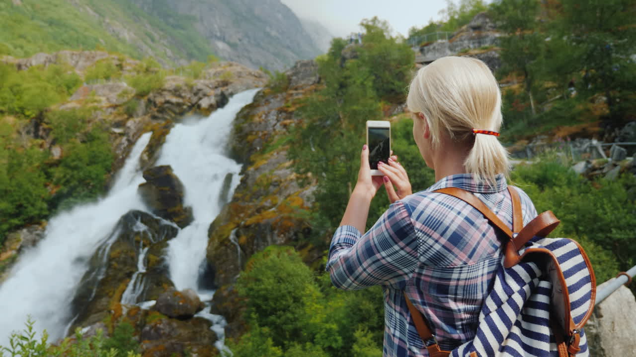 Norveç'teki pitoresk bir şelalenin fotoğraflarını çeken kadın gezgin: Briksdal Buzulu ve görkemli manzara.