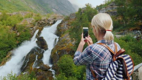 mujer viajera toma fotografías de una pintoresca cascada en noruega glaciar briksdal el majestuoso sc