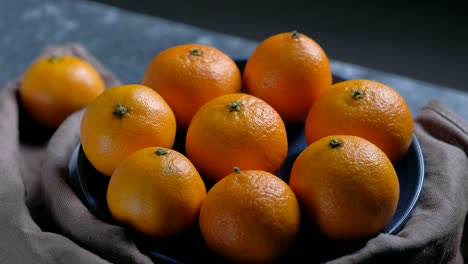 pile of unpeeled round ripe orange mandarin in a plate