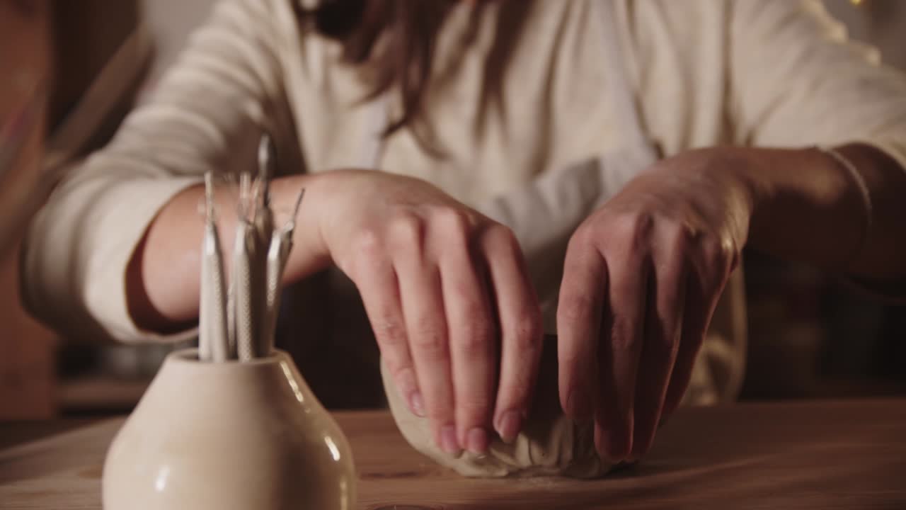 어린 여자 가 손 으로 부드러운 점토 로 그 을 만들고 있다