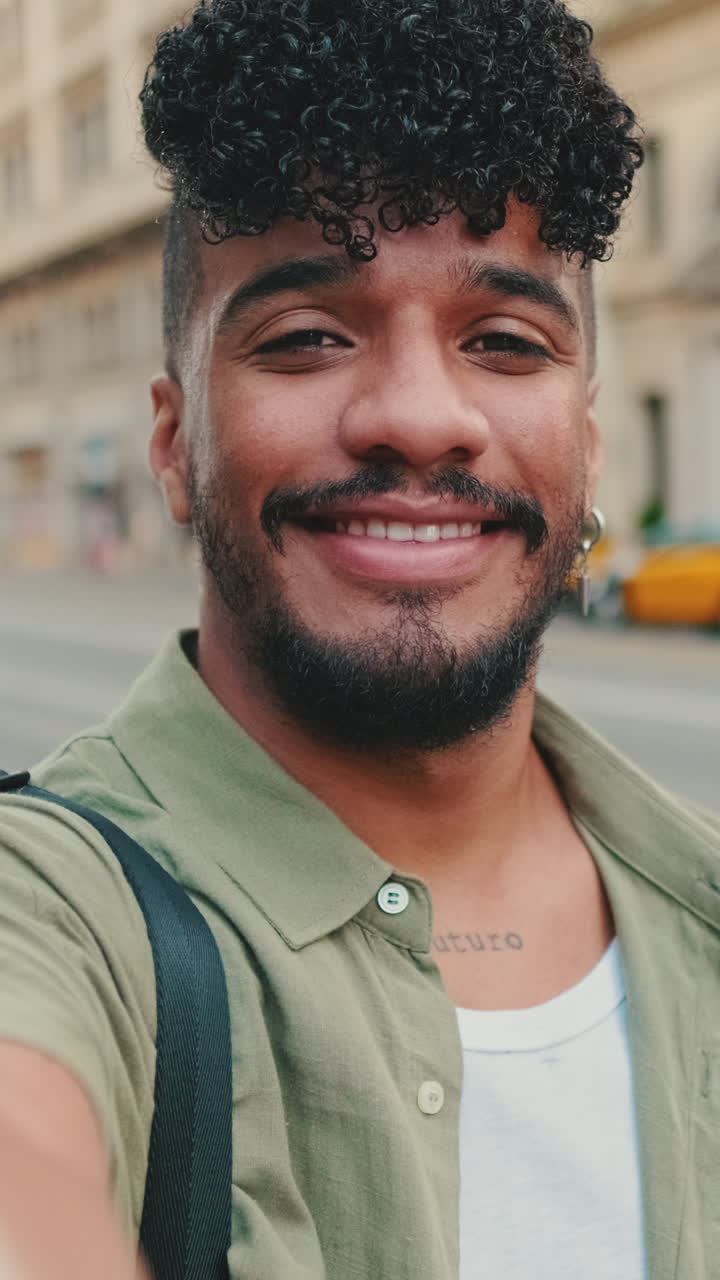 Selfi de un hombre con pelo rizado y barba en la calle