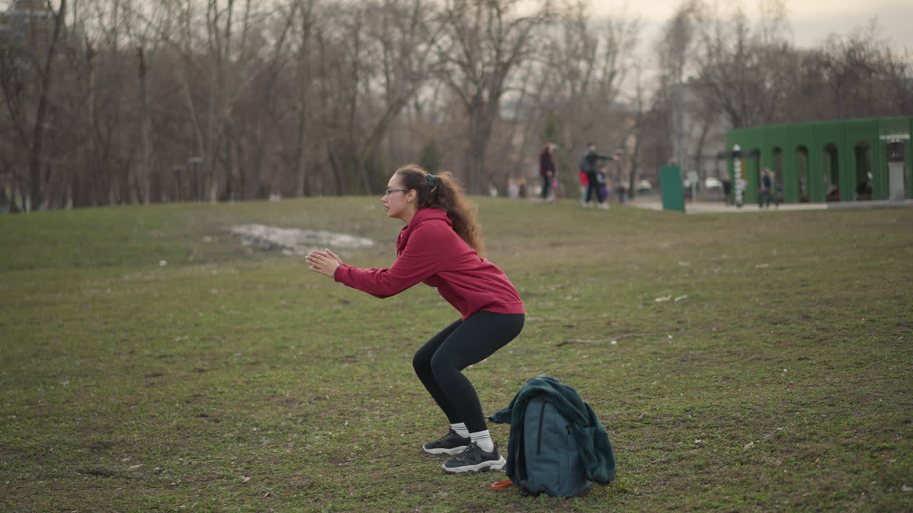 Energetic Woman Running Outdoors, Young Female Engaged In Brisk Outdoor Run With Determination, Youthful Woman Participates In Energetic Jogging Across Scenic Park Landscape Under Overcast Sky