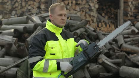 holzfäller in reflektierender jacke. holzfäller mit elektrischer kettensäge. gesägte stämme, brennholz, sägewerk