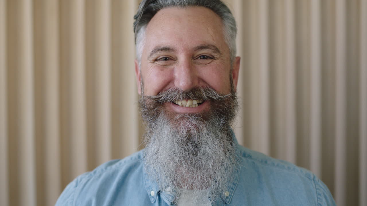 retrato en primer plano de un hombre caucásico maduro con barba elegante riendo alegremente mirando a la cámara disfrutando de un estilo de vida exitoso