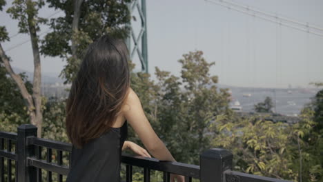 medium shot of beautiful asian girl at prospect point watching lions gate bridge, slowmo