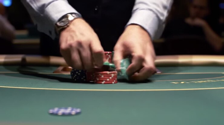 Intense Poker Game: A Close-Up of Skillful Hands Strategically Stacking Poker Chips on a Green Felt Table in a Bustling Casino Atmosphere