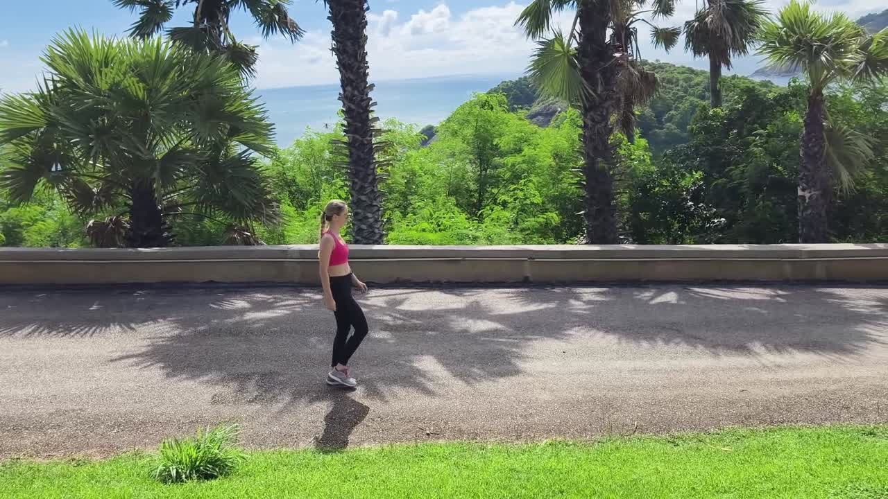 mujer caminando en un parque tropical con vista al océano