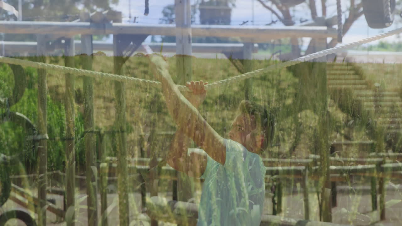 Holding rope over field, man standing near wooden structures in tall grass