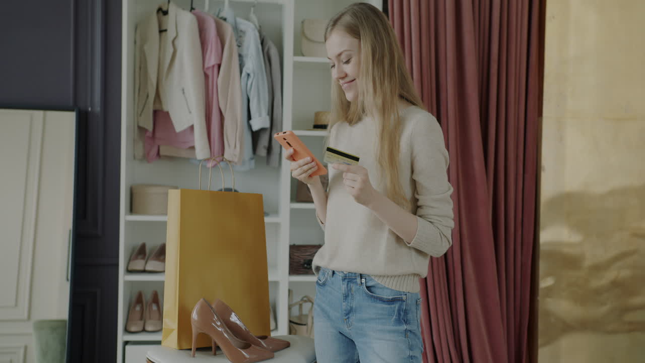 Woman Shopping Online and Paying with Credit Card in Dressing Room