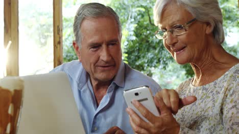 pareja de ancianos usando computadora portátil y discutiendo por teléfono 4k