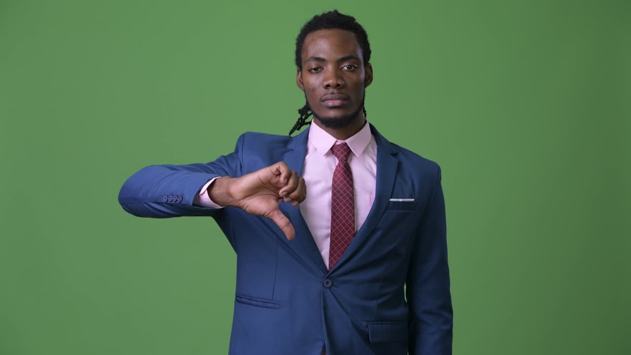Young handsome African businessman with dreadlocks against green background