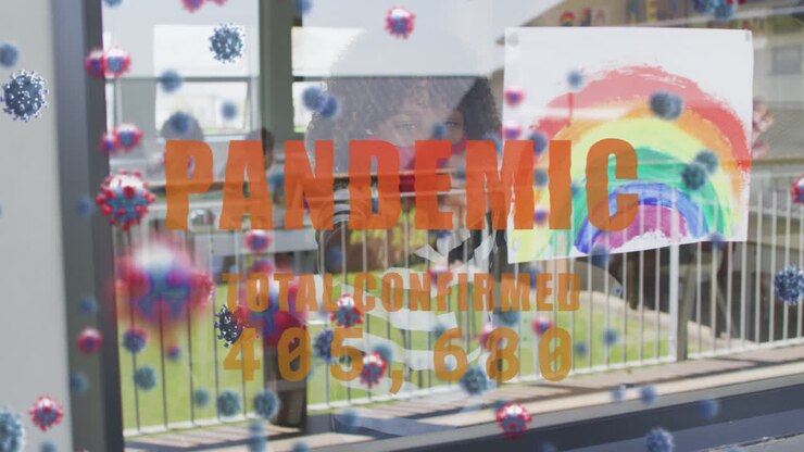 Texto 'Pandemia' com casos em aumento contra menino segurando pintura de arco-íris contra a janela