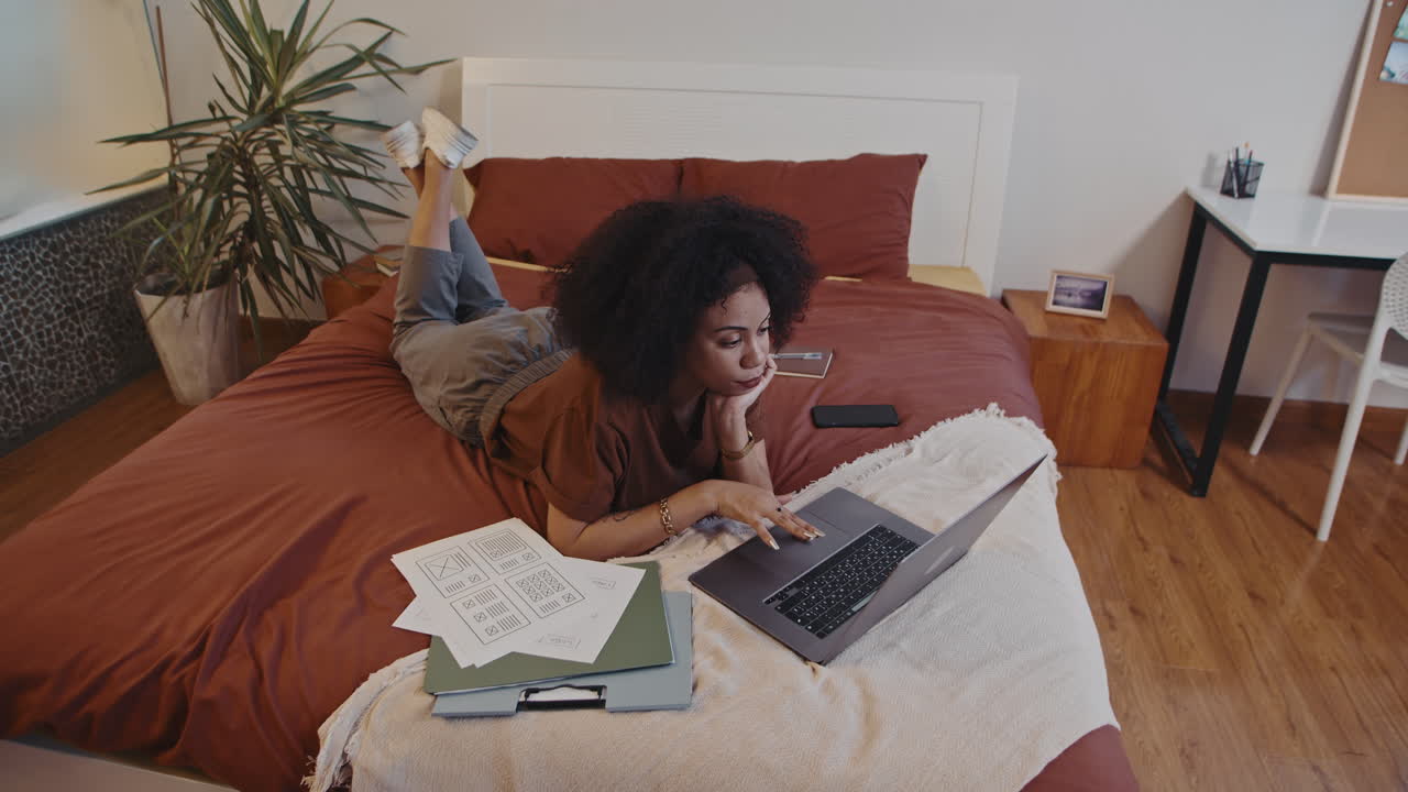 Female Freelance Worker Analyzing Charts on Laptop Working in Bed