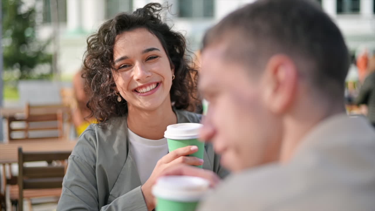 A happy couple outdoors near a cafe. Looking at each other, smiling and talking, coffee. Autumn atmosphere. Slow motion