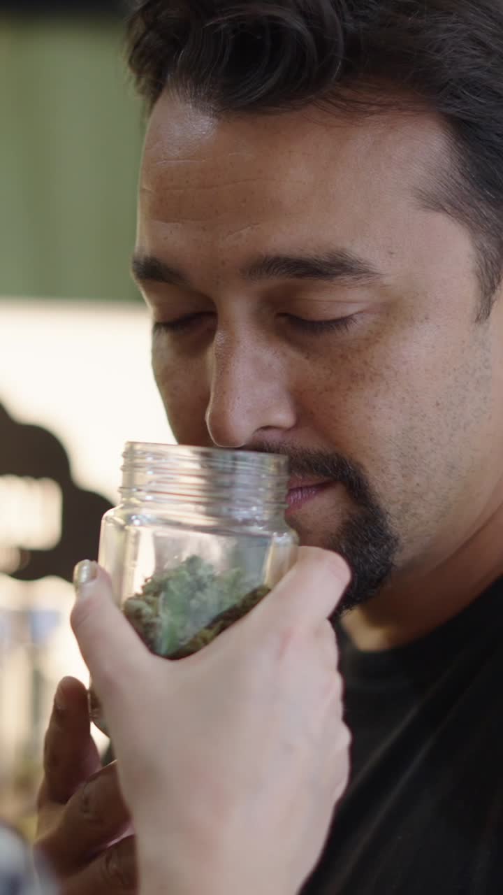 A man smelling marijuana in a jar