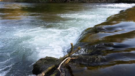 close up of the water flowing over rocks on the river wye in bakewell, uk