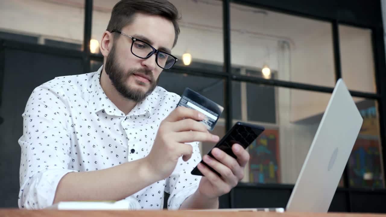 hombre pagando en línea con tarjeta bancaria en su teléfono inteligente
