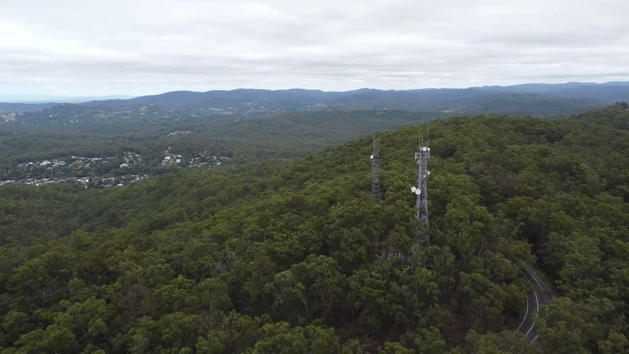 tomada de un dron aéreo de 4k de una torre de transmisión de televisión en la montaña con una carretera sinuosa debajo