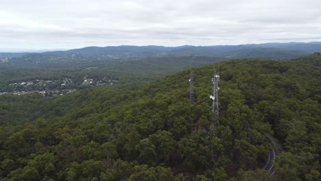 4k aerial drone shot of a tv broadcasting tower on the mountain with winding road below