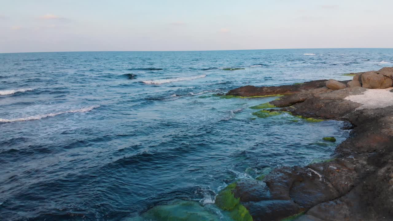 석양에 해변 절벽과 바다를 따라 무인 항공기 비행으로 공중 촬영