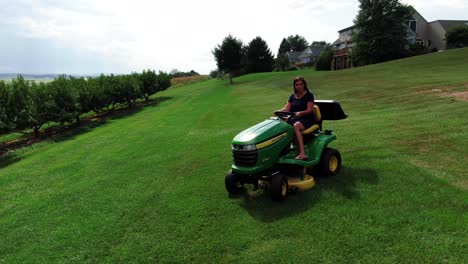 joven hispana cortando césped en cortadora de tractor