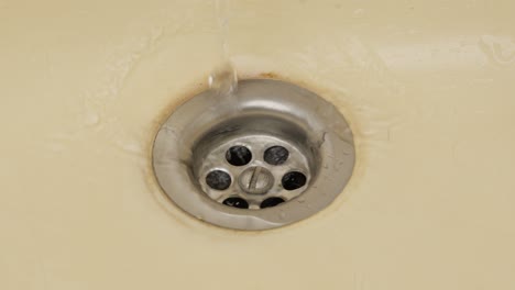 water droplets falling into a stained sink, close-up, slow motion