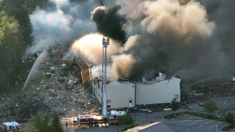 Aerial-drone-footage-of-burning-factory-after-gas-leak-explosion-during-sunny-day---Dark-toxic-fumes-and-smoke-rising-into-nature---zoom-shot