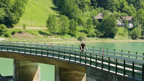 mountain biker rides across a dam on a sunny day
