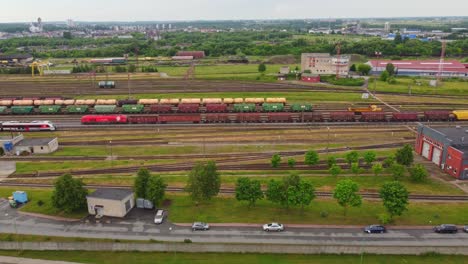 Toma-Aérea-De-Seguimiento-De-Un-Tren-De-Carga-Que-Llega-Al-Patio-De-Trenes-Transportando-Mercancías.