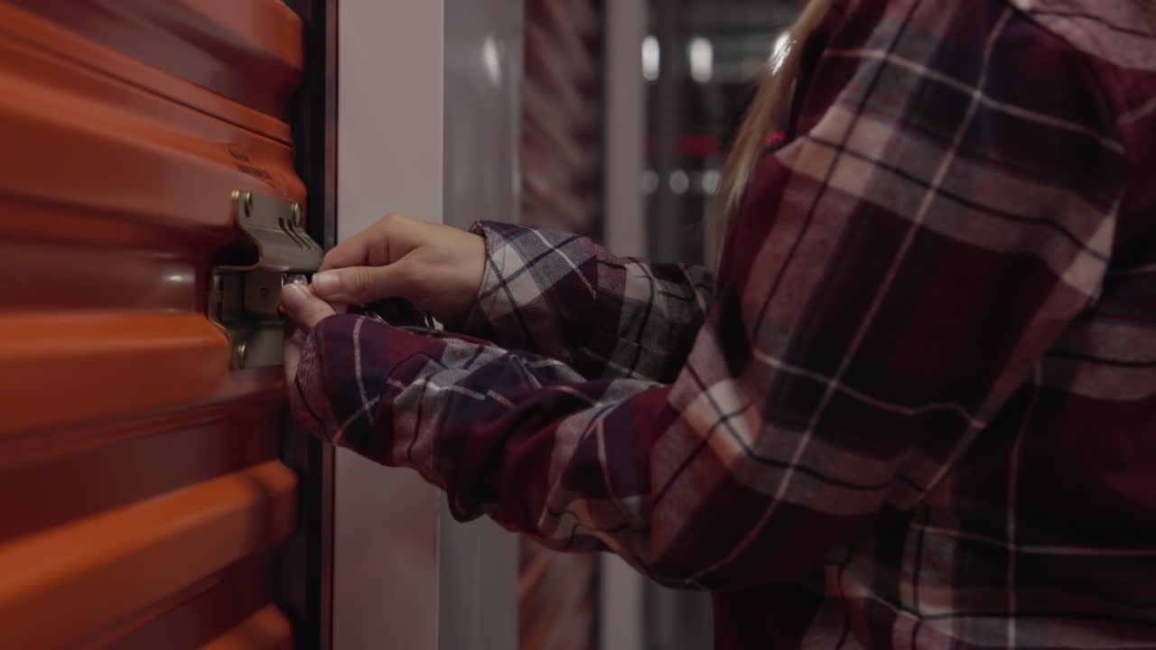 Donna che chiude un deposito con una chiave, indossando una camicia a quadri.