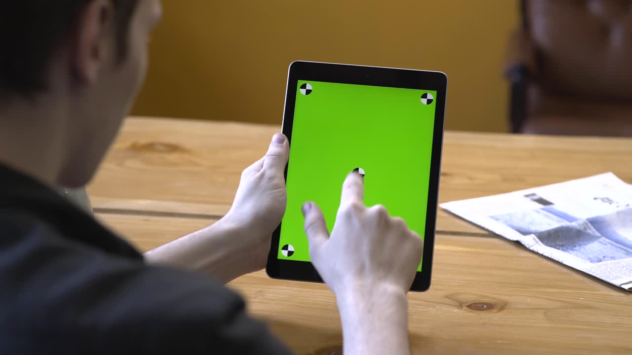 카페에서 초록색 화면을 가진 태블릿을 사용하는 남자