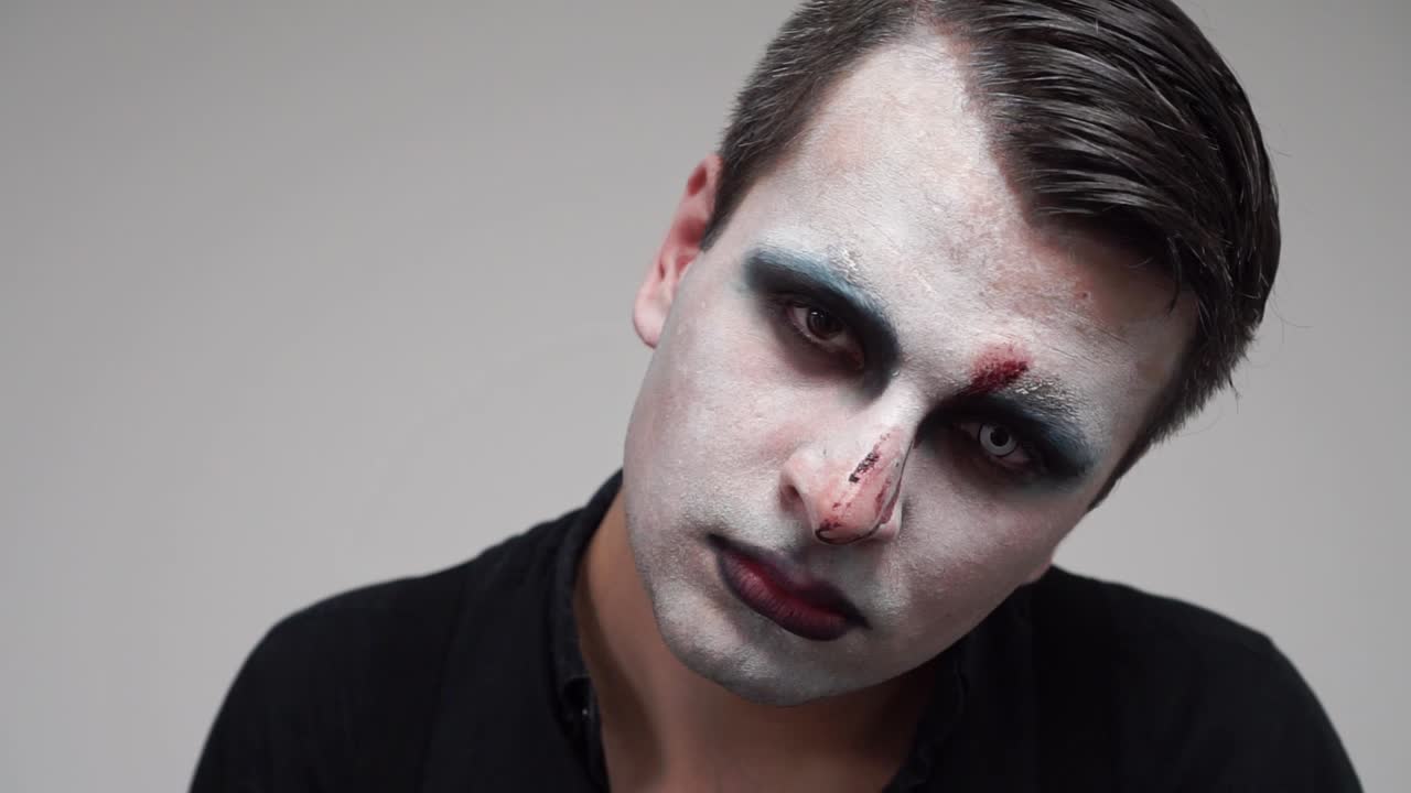 Man with face paint looking at camera and showing tongue, portrait closeup, slowmo