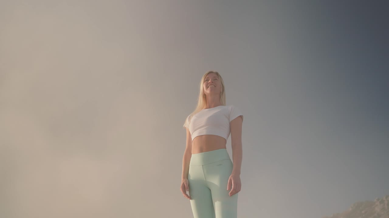 una mujer atlética delgada se para en la niebla y se pone de la mano disfrutando de una vista mágica