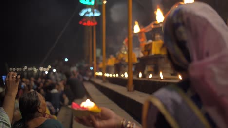 woman holds candle at ganga aarti ceremony