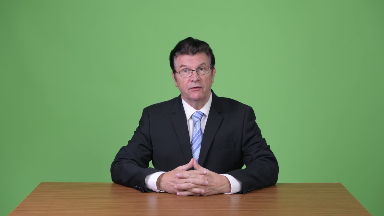 Senior handsome businessman talking to camera