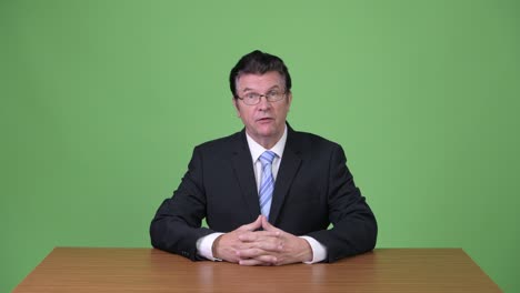 senior handsome businessman talking to camera