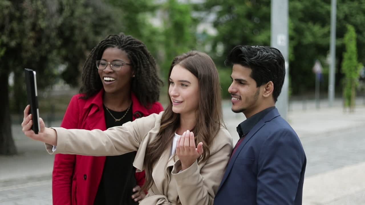 tres jóvenes teniendo chat de video en la tableta afuera