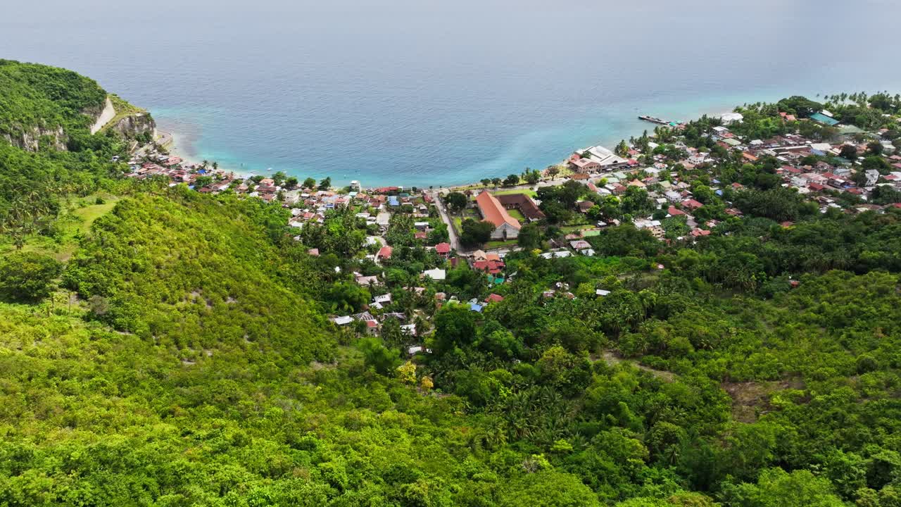 Rigogliosa collina verde si apre su un insediamento costiero, costa turchese, Cebu, Boljoon